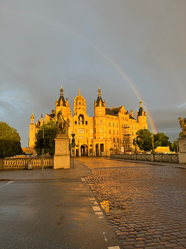 Das Schweriner Schloss in der Abendsonne und darüber ein Regenbogen